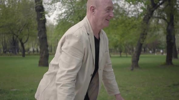 Positive Grandfather and Cute Grandson in Checkered Shirt High Five in the Park