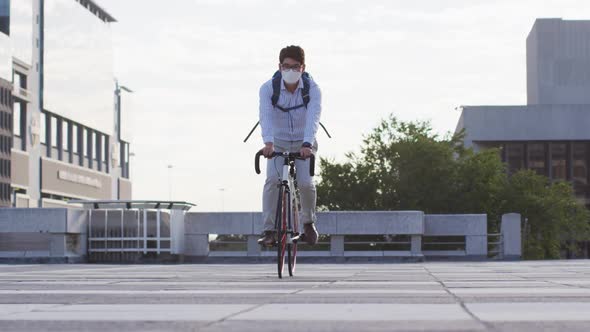 Asian man wearing face mask riding bicycle on the roof of corporate park