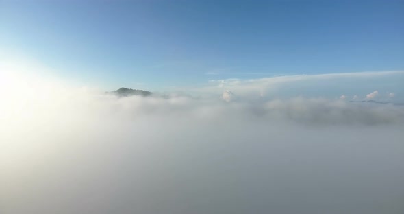 Aerial view of sunrise with fog above forest and mountains.