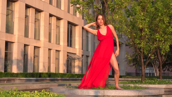 Beautiful Young Girl Dancing on the Street of a Modern Building of a Business Center in the Sunset