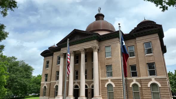 Hays County Courthouse in San Marcos Texas. USA American flag and Texas TX flag. Rising reveal of ar