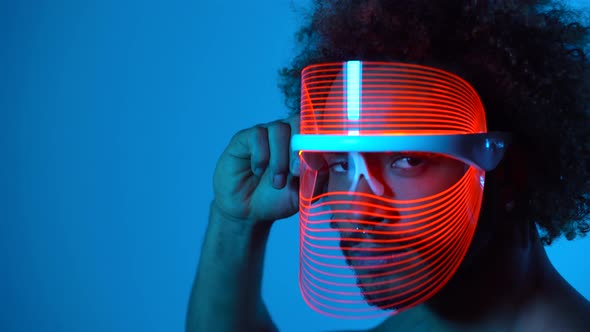 Man wearing light therapy mask against blue wall