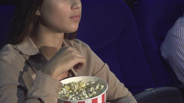 A Close-up of How a Girl Eats Popcorn and Shows a Sign of Silence