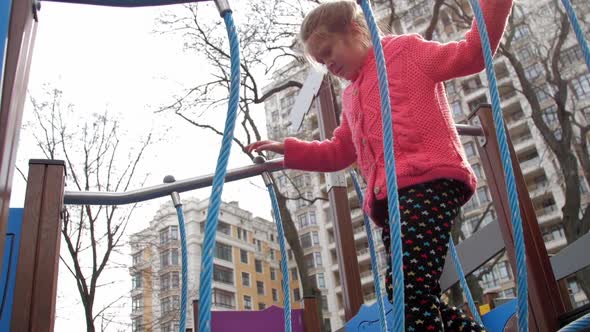 Scared Young Lady Steps on Suspension Bridge on Playground