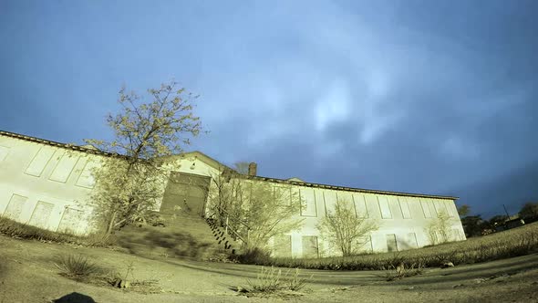 NIGHT LAPSE - Moon and clouds moving fast behind a big abandoned building.  Bug blue sky with a low