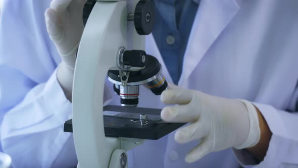 Close Up of Scientist in Medical Labcoat Performing Research in Lab Looking Through Microscope