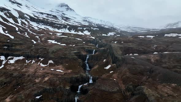 Flight Over Stunning Cascades Of Klifbrekkufossar Waterfall In Mjoifjordur, Eastern Iceland. Aerial