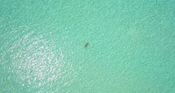 Aerial drone view of a woman floating and swimming on a tropical island