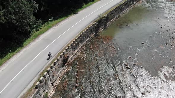 Fit Female Cyclist Training on Road Bicycle in Mountains Alone River