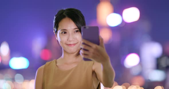 Woman taking selfie on cellphone at night