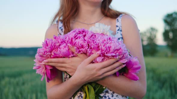 Woman Holding Pink Flowers Peonies Walking in the Field Wheat Field at Sunset