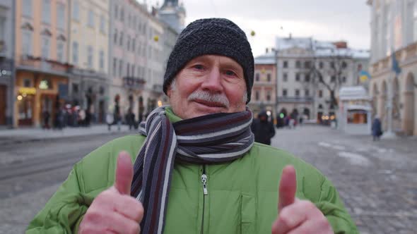 Senior Old Man Grandfather Tourist Smiling Showing Thumbs Up in Winter City Center of Lviv Ukraine