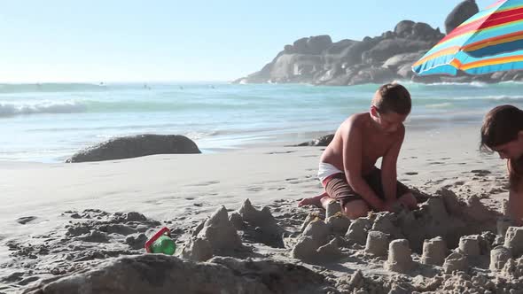 Boy and Girl Making Sandcastles on Beach
