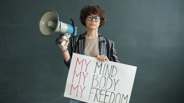 Portrait of Strong Woman Holding My Freedom Banner and Megaphone Standing on Black Background