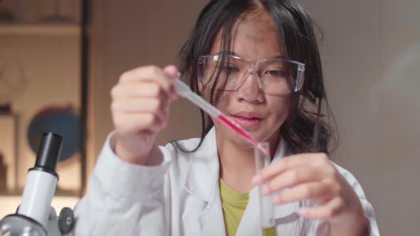 Young Asian Scientist Girl With Dirty Face Mixes Chemicals In Test Tube. Child Learn With Interest