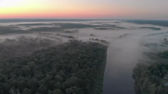 Aerial View of a Misty Winding River in the Middle of a Forest in a Remote Rural Area