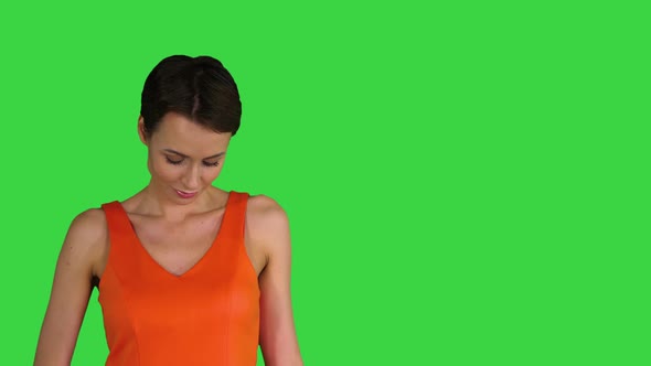 A Beautiful, Cheerful Woman Straightens Her Dress on a Green Screen, Chroma Key.