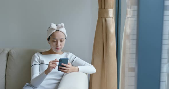 Woman use of smart phone with paper mask at home