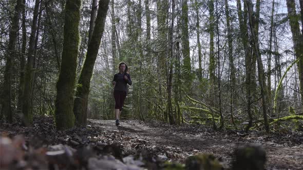 Caucasian Woman Trail Running in the Green Forest