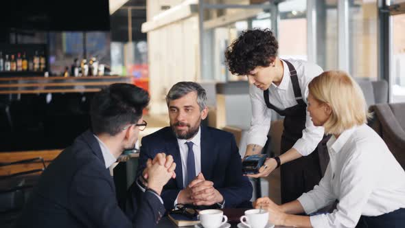 Successful Businessman Making Digital Online Payment in Cafe Using Smartphone