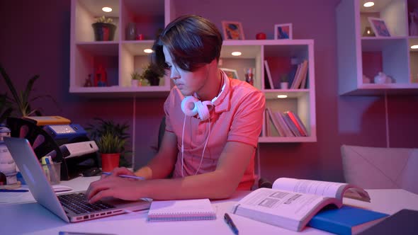 Male student working with book at home.