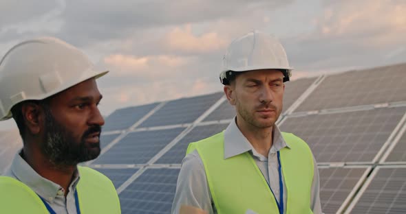 Close Up of Diverse Male Engineers Walking at Solar Farm and Discussing Efficient Plan of