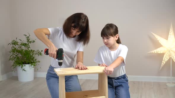 Happy Family Mother and Daughter Assembling Wooden Furniture Together with Screwdriver