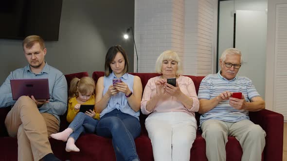 Addicted To Gadgets Family Using Mobile Phone, Tablet, Laptop Ignoring Each Other at Home. Obsession