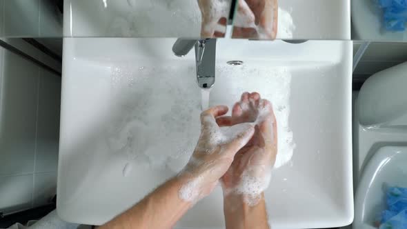 Young Man Washing Hands in Bathroom at Home