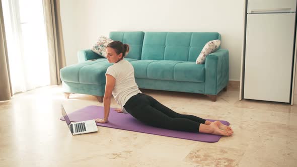 Attractive Young Woman Doing Yoga Stretching Yoga Online at Home.