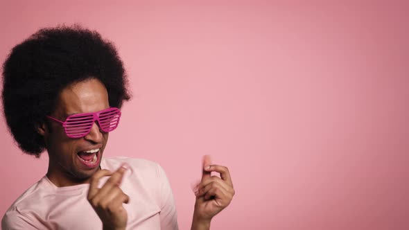 Young African man smiling and dancing in the pink glasses