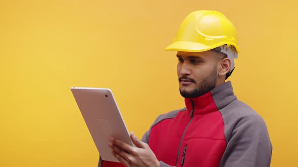 Young Engineer with Yellow Helmet Using Tablet