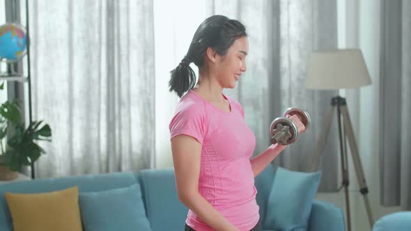 Young Asian Woman With Dumbbells Exercising At Home