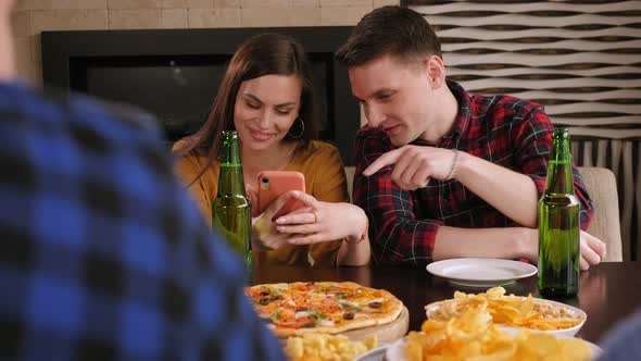 Friends Are Sitting in a Cafe with Phones Drinking Beer and Eating Pizza