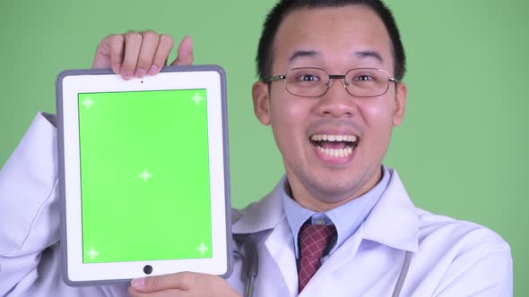 Face of Happy Asian Man Doctor Showing Digital Tablet