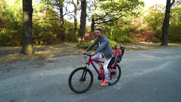 Father and little daughter on bike ride in park