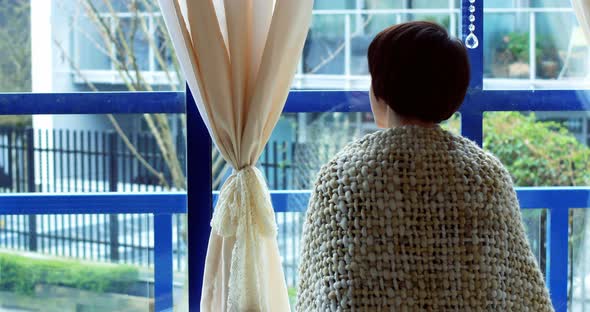 Rear view of woman looking through window