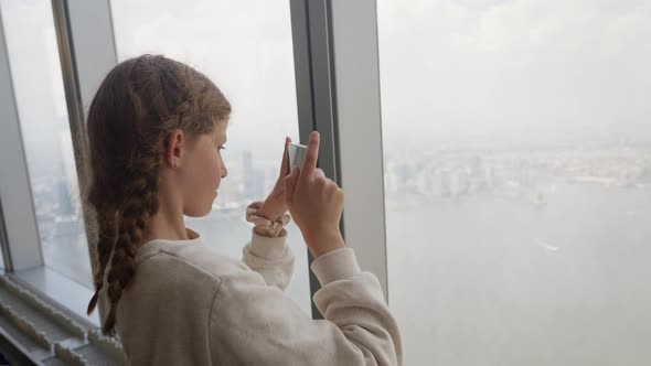 Girl With Smartphone At Window In Skyscraper Filming New York City