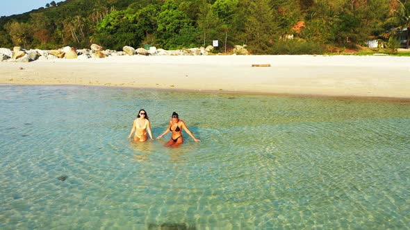 Beautiful happy ladies travelling in the sun at the beach on paradise white sand and blue background