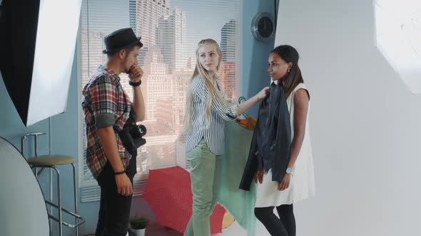 Photo Session in Modern Studio: Stylist and Photographer Choosing Clothes for Black Model's 