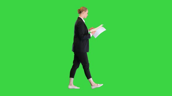 Young Business Woman Looking Through Documents While Walking on a Green Screen Chroma Key