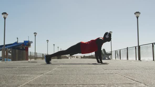 Focused african american man doing press ups, exercising outdoors by the seaside