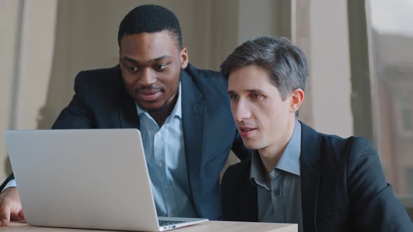 Two Pensive Male Colleagues in Office Talking Discussing Problem with Online Server Looking at