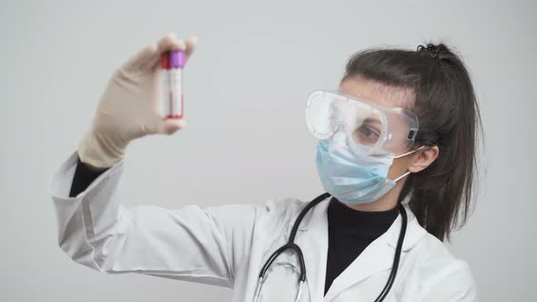 Woman with White Coat and Gloves Checking Coronavirus Blood Tests In Hospital Laboratory