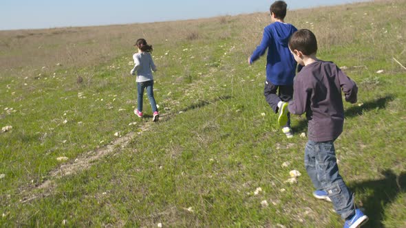 Young kids running together on green hills outdoors in nature