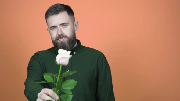 Handsome man holds out a rose to the camera