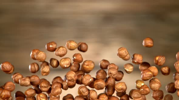 Super Slow Motion Shot of Flying Hazelnuts After Being Exploded on Wooden Background at 1000 Fps