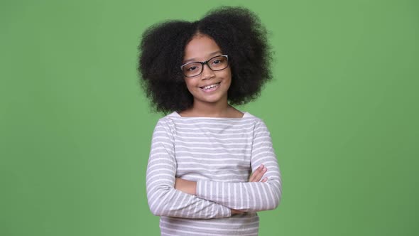Young Happy African Girl with Afro Hair Smiling While Crossing Arms Against Green Background