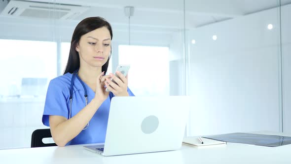 Young Doctor Browsing Online on Phone in Hospital