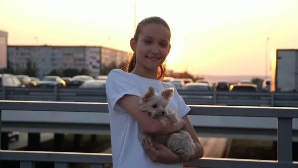 Teenage Girl in Tshirt Holds Small Puppy at Back Sunset